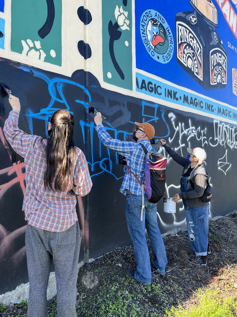 An image of Kimfer during a volunteer paint day maintaining the murals for the SODO Track project with 4Culture.
