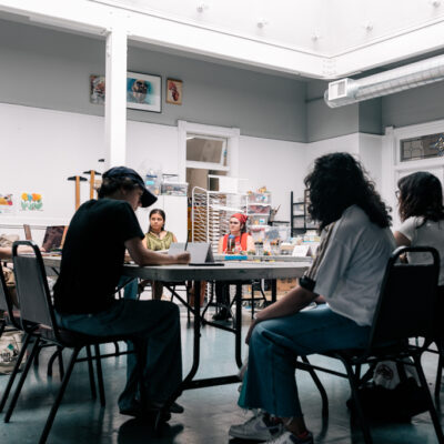 The Summer 2024 Kirkland MAP cohort working together on their mural design inside the Kirkland Arts Center. Teaching Artists, Teaching Artists Natalia Sotelo and Bry Sutherland can be seen.