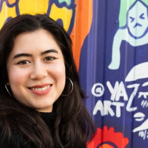 Yaz who is the Programs Specialist at Urban ArtWorks created her mural to bring energy, color, and warmth to the city. She says “My piece is called ‘Miss You, Sun’… in Seattle we have a lot of gloomy days and some people get seasonal depression, and I really wanted people to feel a sense of energy from my piece. So, it's a lady holding the sun and she's thinking, ‘I miss you sun’.”