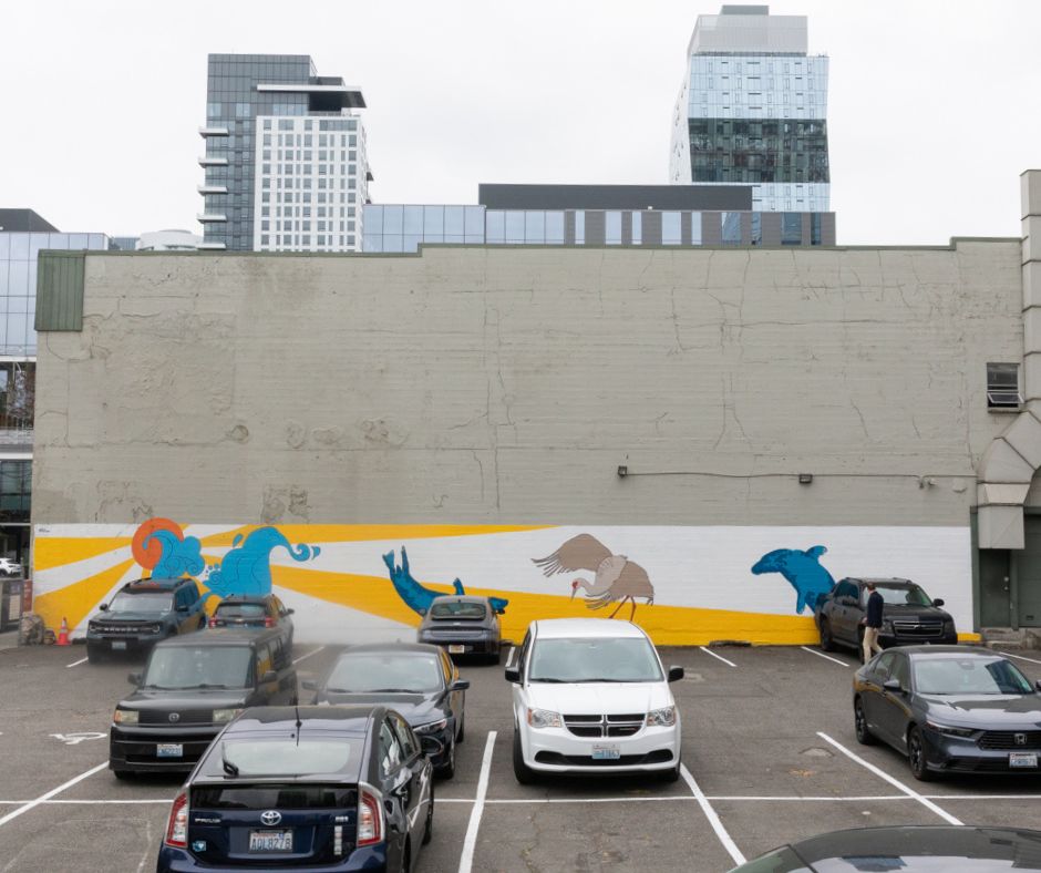 August Donica's mural at 401 8th Ave N. It has birds from the Pacific Northwest with an orange sun and yellow and white lines coming out of the sun.