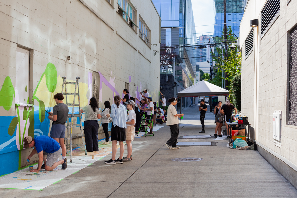 the volunteers that came to paint the mural by Sophie Fong at 401 8th Ave N. A tent can be seen with volunteers painting the mural.