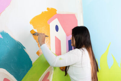 Velvet, who is a teenage, East Asian, and female-presenting person, painting She has long straight hair with dark brown and green accents. She stand at a medium height.